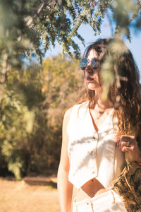 Young woman standing against trees