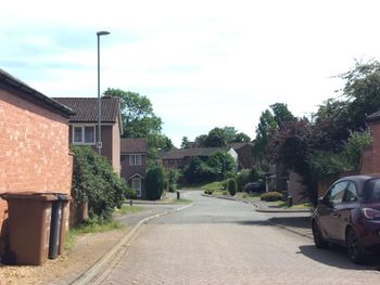 Cars on street by buildings against sky