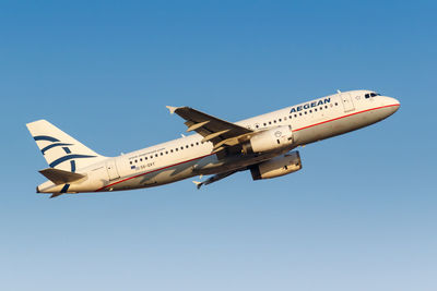 Low angle view of airplane flying against clear blue sky