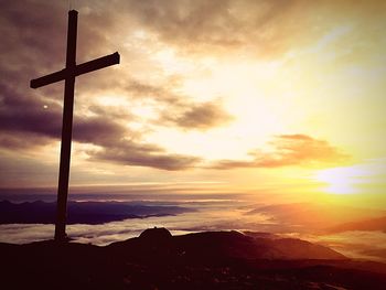 Silhouette cross against sky during sunset