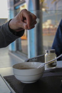 Close-up of person hand sprinkling seasoning on drink