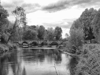 Bridge over river against cloudy sky