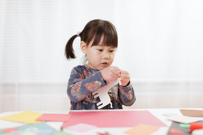 Cute girl looking away while sitting on table