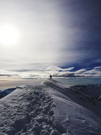 Mid distance of person walking on snowy mountain against sky