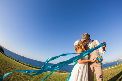 Woman holding umbrella against clear blue sky