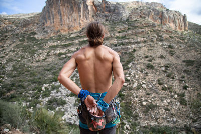 Rear view of shirtless man standing on rock