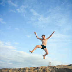 Low angle view of boy jumping against sky