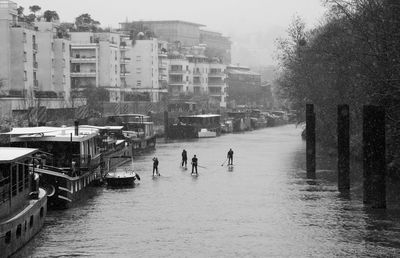 People on river amidst buildings in city