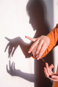 Shadow of woman cutting fingernails on wall