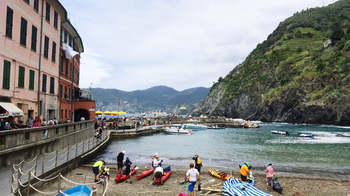 People on boats in sea against mountains