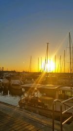 Boats moored at harbor against sky during sunset