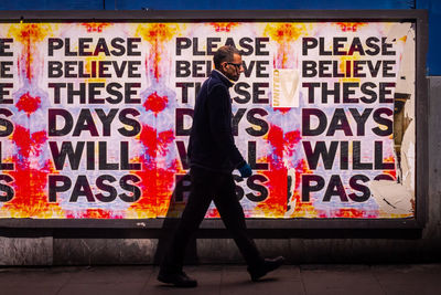 Man standing by graffiti on wall