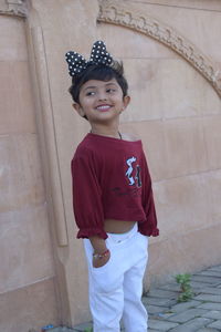 Portrait of smiling girl standing against wall