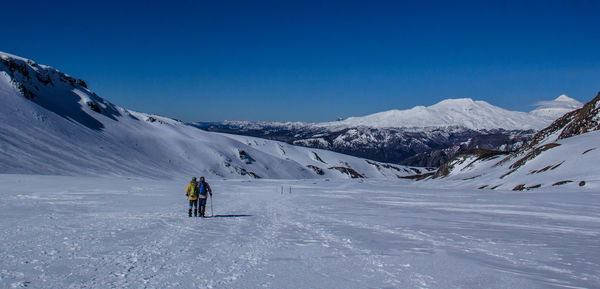 Person skiing on snow covered mountain against blue sky