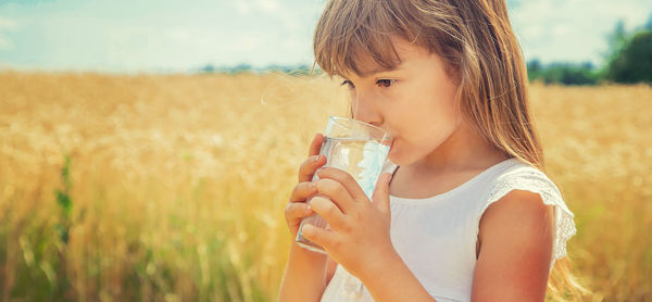 Portrait of young woman drinking water in park