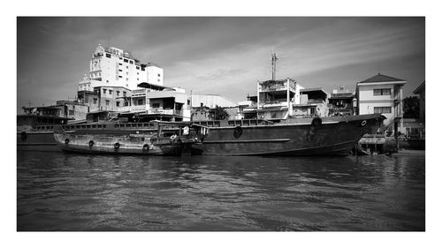 Boats in river against buildings on sunny day