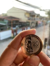 Close-up of hand holding a 20 pesos coins