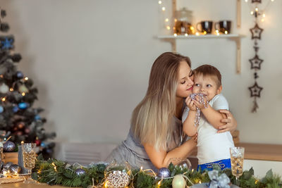 Mother embracing son while sitting at home