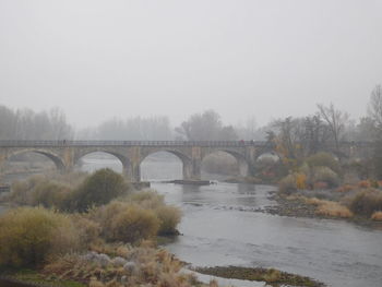 Arch bridge over river against clear sky