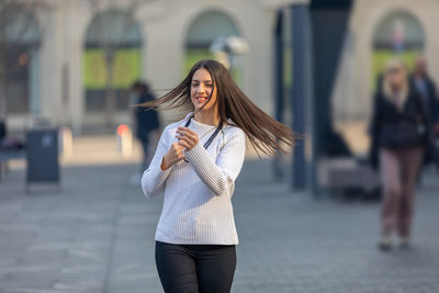 Beautiful teenager walking down the street. hair fluttering in the wind.girl expressing good emotion