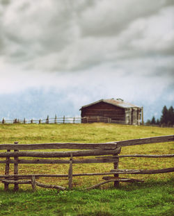 Wooden fence on grassy field against sky