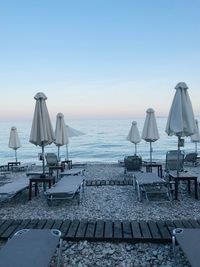 Deck chairs on beach against clear sky