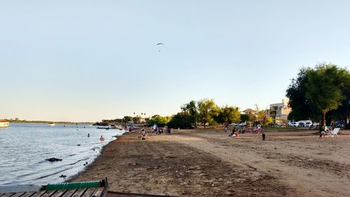 People at beach against clear sky