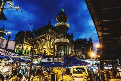 Crowd in illuminated city against sky at night