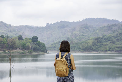 Rear view of woman standing at lake