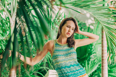 Thoughtful young woman standing by trees