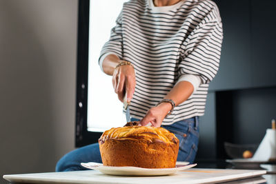 Young beautiful woman cutting homemade apple pie at the modern kitchen