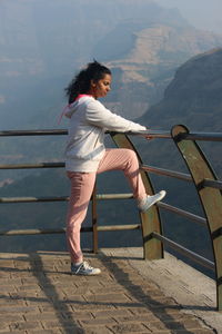 Full length of woman on railing against mountains