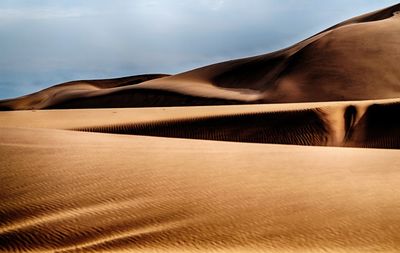 Sand dunes in desert against sky