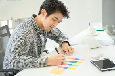 Mid adult man using smart phone while sitting on table