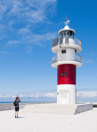 Lighthouse on beach against sky