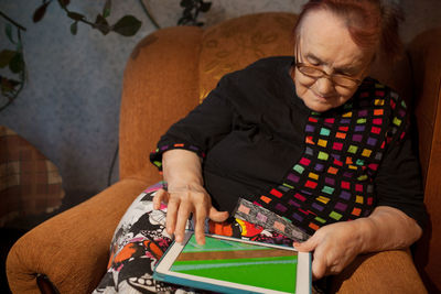 Woman using digital tablet while sitting on chair at home