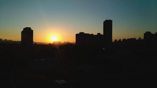 Silhouette cityscape against sky during sunset