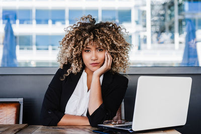 Confident hispanic afro business woman in cafe working on laptop and mobile phone.tech and lifestyle