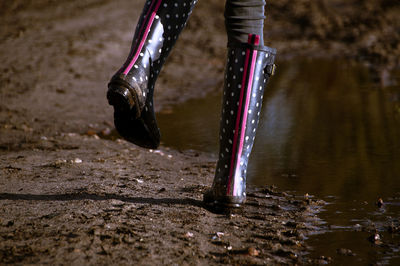 Low section of woman walking on dirt road