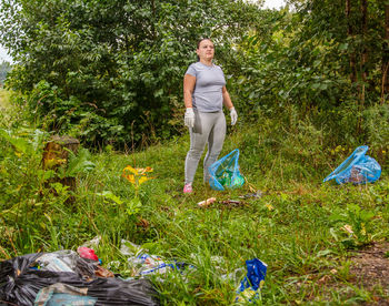 A woman volunteer removes garbage from a landfill near the river. horizontal photo