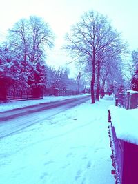 Snow covered road passing through field