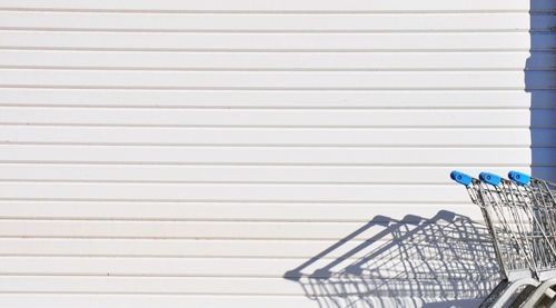 Cropped shopping trolleys against white wall