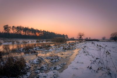 Scenic view of snow covered land during sunset