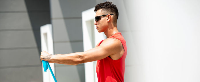 Side view of young man exercising against wall