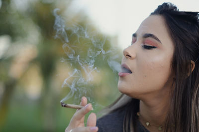 Portrait of young woman smoking outdoors