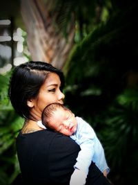 Close-up of mother carrying son against trees