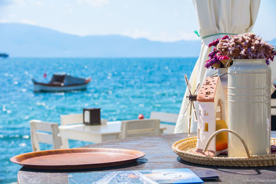 Lounge chairs and table at sea shore against sky