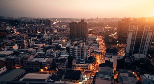 High angle view of modern buildings in city against sky during sunset