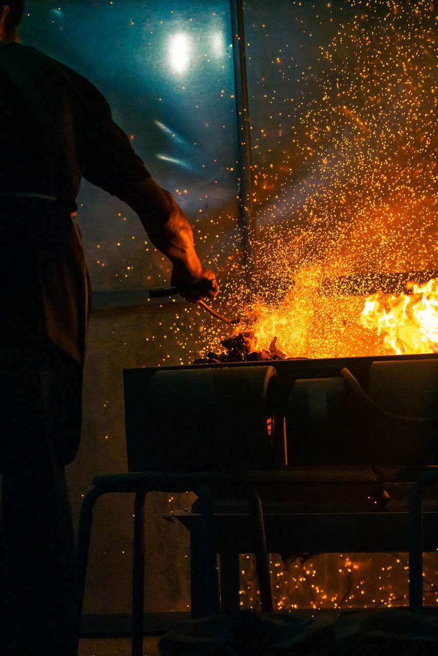 MAN WORKING WITH FIRE IN THE DARK