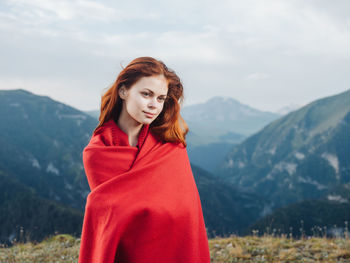 Beautiful young woman standing against mountain range